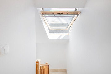 Stairs of a residential house with an attic with a tilt-and-turn skylight made of glass and wood