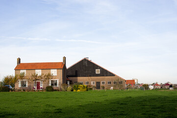 Dutch farm with a larger barn and  a green meadow in the foreground in Arnhem in the Netherlands