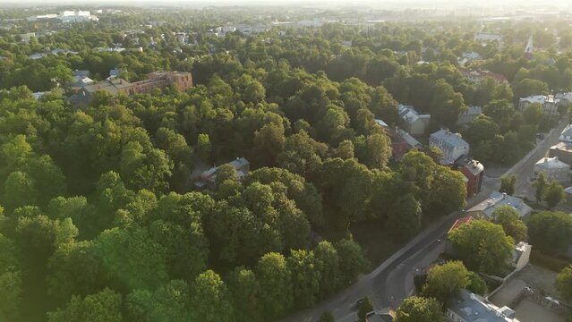 Green cityscape. Green city aerial view. Old medieval church. Modern and ecological city park with green trees. Top down view of residential houses and old red church castle in the background.
