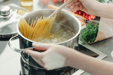 Girl cooking pasta spaghetti in pot - 549053928