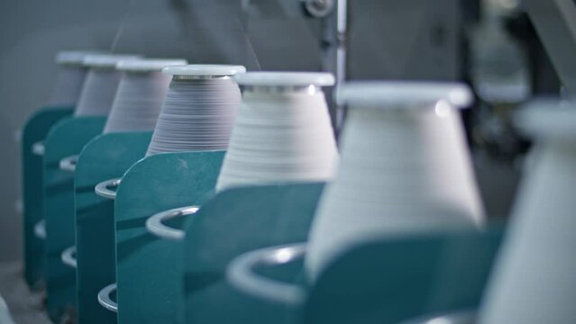 Cotton yarn on bobbin. Spool of thread closeup on clothing factory. Textile fabric. Industrial equipment. Knitwear production
