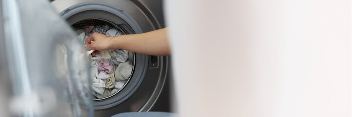 Woman loading washing machine with dirty clothes, taking out clean stuff