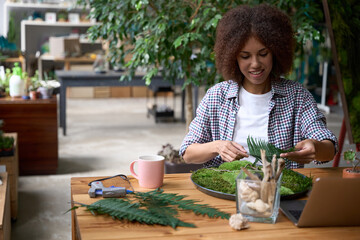 Cheerful woman enjoying work in florist office with moss