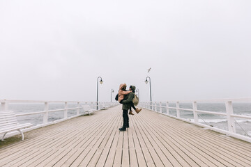 Couple walk in winter on jetty by the sea