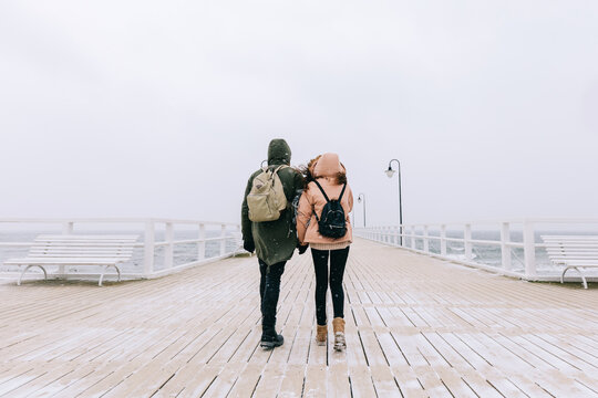 Couple walk in winter on jetty by the sea