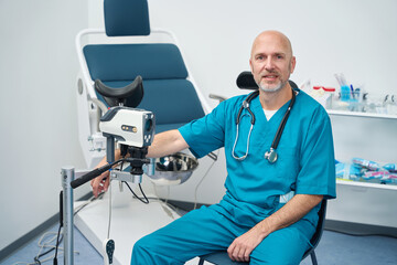 Doctor is sitting next to the gynecological examination chair - obrazy, fototapety, plakaty