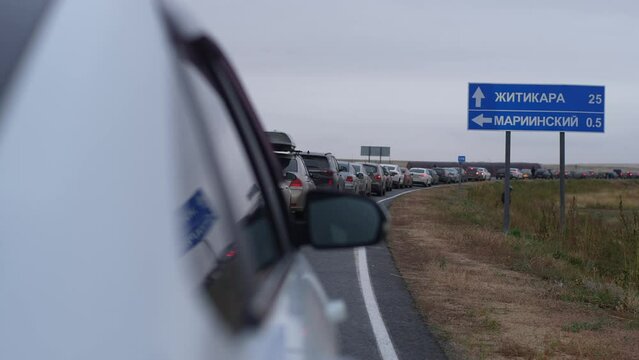 Tracking shot of long queue of cars standing in large traffic jam at customs border crossing between Russia and Kazakhstan after announcement of partial mobilization in Russia. Shooting in slow motion