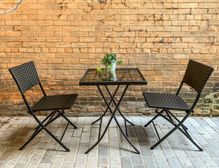Fototapeta na wymiar table and chairs on an outdoor patio beside a brick wall