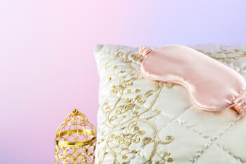 White silk pillow with pink sleep mask and golden candlestick on a gradient background. luxury bed linen. Pleasant sleep and relaxing at home concept with soft luxury cushion