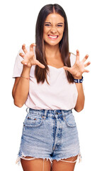 Young hispanic woman wearing casual white tshirt smiling funny doing claw gesture as cat,...