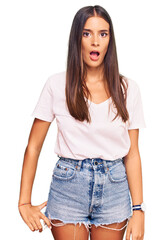 Young hispanic woman wearing casual white tshirt in shock face, looking skeptical and sarcastic, surprised with open mouth