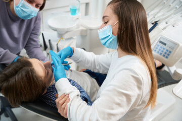 Woman dentist removes a tooth to a young patient