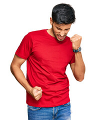 Young handsome man wearing casual red tshirt celebrating surprised and amazed for success with arms...