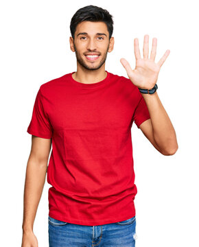 Young handsome man wearing casual red tshirt showing and pointing up with fingers number five while smiling confident and happy.