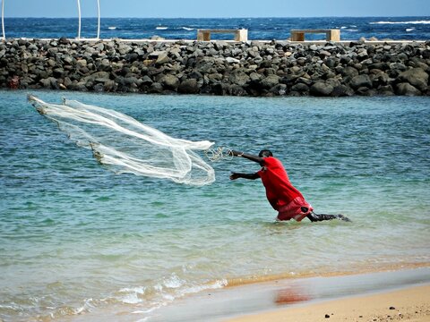 HOMBRE PESCANDO CON RED EN PLAYA DE DAKAR, SENEGAL