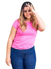 Fototapeta premium Young caucasian woman wearing sportswear doing ok gesture with hand smiling, eye looking through fingers with happy face.