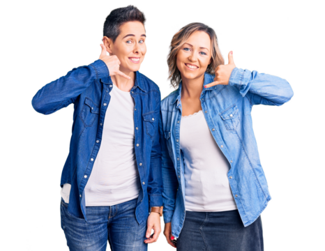 Couple of women wearing casual clothes smiling doing phone gesture with hand and fingers like talking on the telephone. communicating concepts.