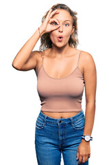 Beautiful caucasian woman wearing casual clothes doing ok gesture shocked with surprised face, eye looking through fingers. unbelieving expression.