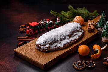 Christmas pie stollen with marzipan, berries and nuts on a dark concrete background