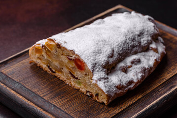 Christmas pie stollen with marzipan, berries and nuts on a dark concrete background