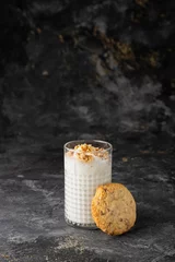 Schilderijen op glas Vertical closeup of a white smoothie in a clear glass with a cookie leaning on it. © Galip Kürkcü/Wirestock Creators