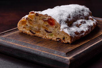 Christmas pie stollen with marzipan, berries and nuts on a dark concrete background
