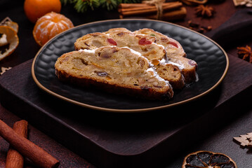 Christmas pie stollen with marzipan, berries and nuts on a dark concrete background