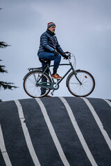 Naklejka premium Copenhagen, Denmark A man stands on a bicycle in the Superkilen park in Norrebro.