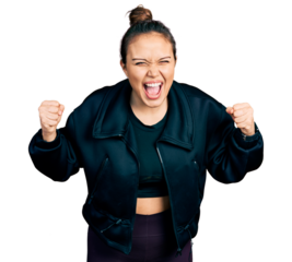 Young hispanic girl wearing sportswear angry and mad raising fists frustrated and furious while shouting with anger. rage and aggressive concept.