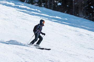 Naklejka na ściany i meble Amateur female skier sliding down the slope at a mountain resort.