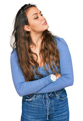 Young hispanic girl wearing casual clothes looking to the side with arms crossed convinced and confident