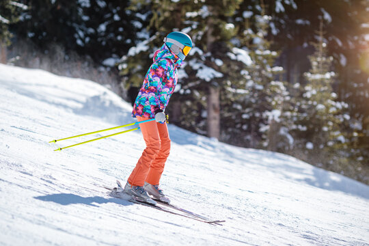 Young skier learning to slide down the slope on a sunny day at a mountain resort.
