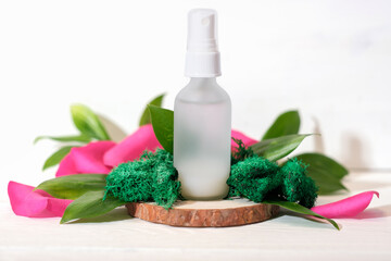 Obraz na płótnie Canvas Mock up glass spray bottle on wooden saw cut podium with rose petals and moss and leaves. beauty fermented cosmetic skin care product, 