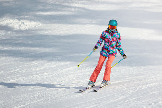 Young female skier learning to slide down the slope on a sunny day at a mountain resort. Copy space.
