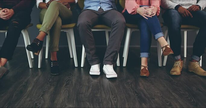 Shoes, interview and recruitment with business people waiting in line for a meeting with human resources. HR, hiring and candidate group in a waiting room sitting in a row on chairs in an office