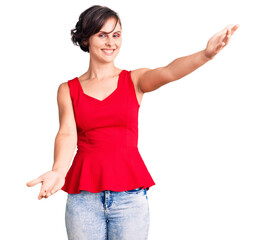 Beautiful young woman with short hair wearing casual style with sleeveless shirt looking at the camera smiling with open arms for hug. cheerful expression embracing happiness.