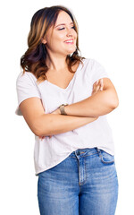 Young beautiful caucasian woman wearing casual white tshirt looking to the side with arms crossed convinced and confident