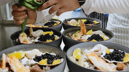 The chef decorates a dish with crab and black caviar. Seafood dish served on stones. Restaurant kitchen, the chef prepares a signature dish