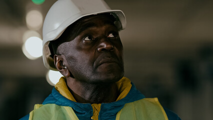 Close-up serious focused mature man professional civil engineer in protective helmet inspects develops plan businessman builder experienced construction worker foreman evaluates planning work process
