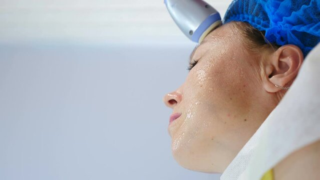 Modern beauty clinic with hardware cosmetology. Vertical video. Middle aged woman getting rf lifting skincare facial procedure. skin rejuvenation. Female client getting face rf-lifting treatment. 4 k