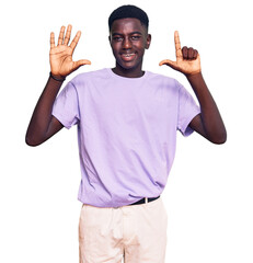 Fototapeta premium Young african american man wearing casual clothes showing and pointing up with fingers number seven while smiling confident and happy.