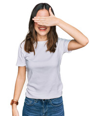 Fototapeta premium Young beautiful woman wearing casual white t shirt smiling and laughing with hand on face covering eyes for surprise. blind concept.