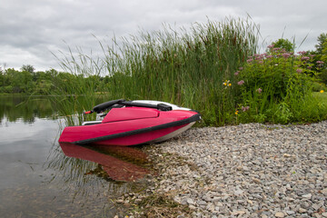 An old jetski parked at a gravel boat launch on a river