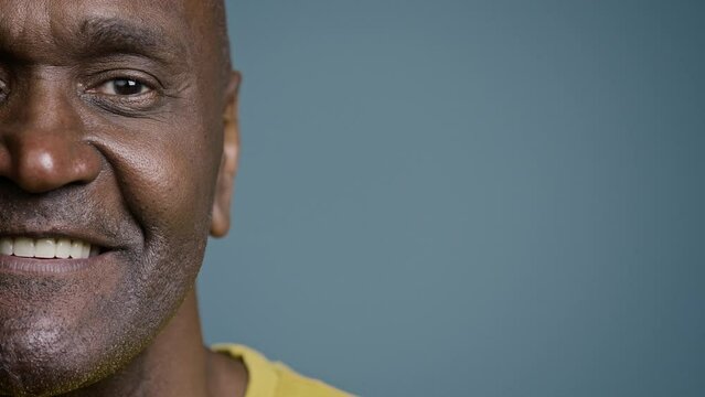 Close-up half male face with joyful expression mature african american man looking at camera smiling white healthy toothy smile happy customer satisfied with service posing in gray background studio