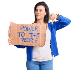 Young beautiful woman holding power to the people banner with angry face, negative sign showing dislike with thumbs down, rejection concept