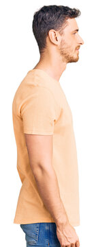 Handsome young man with bear wearing casual yellow tshirt looking to side, relax profile pose with natural face with confident smile.