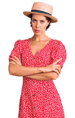 Young beautiful woman wearing summer hat skeptic and nervous, disapproving expression on face with crossed arms. negative person.