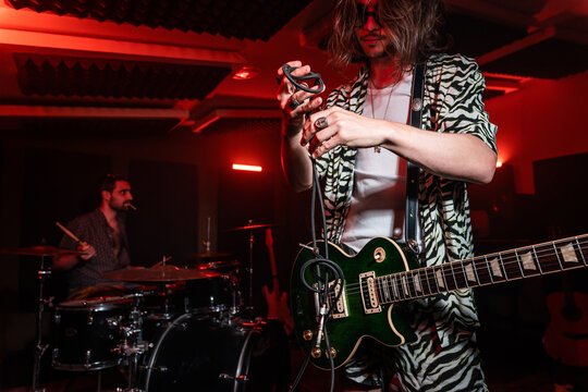 Male Guitarist Unraveling Wire From Electric Guitar