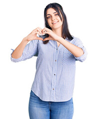 Young beautiful girl wearing striped shirt smiling in love showing heart symbol and shape with hands. romantic concept.