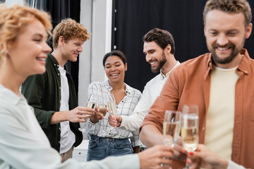 Smiling interracial business people clinking glasses of champagne during corporative party in office